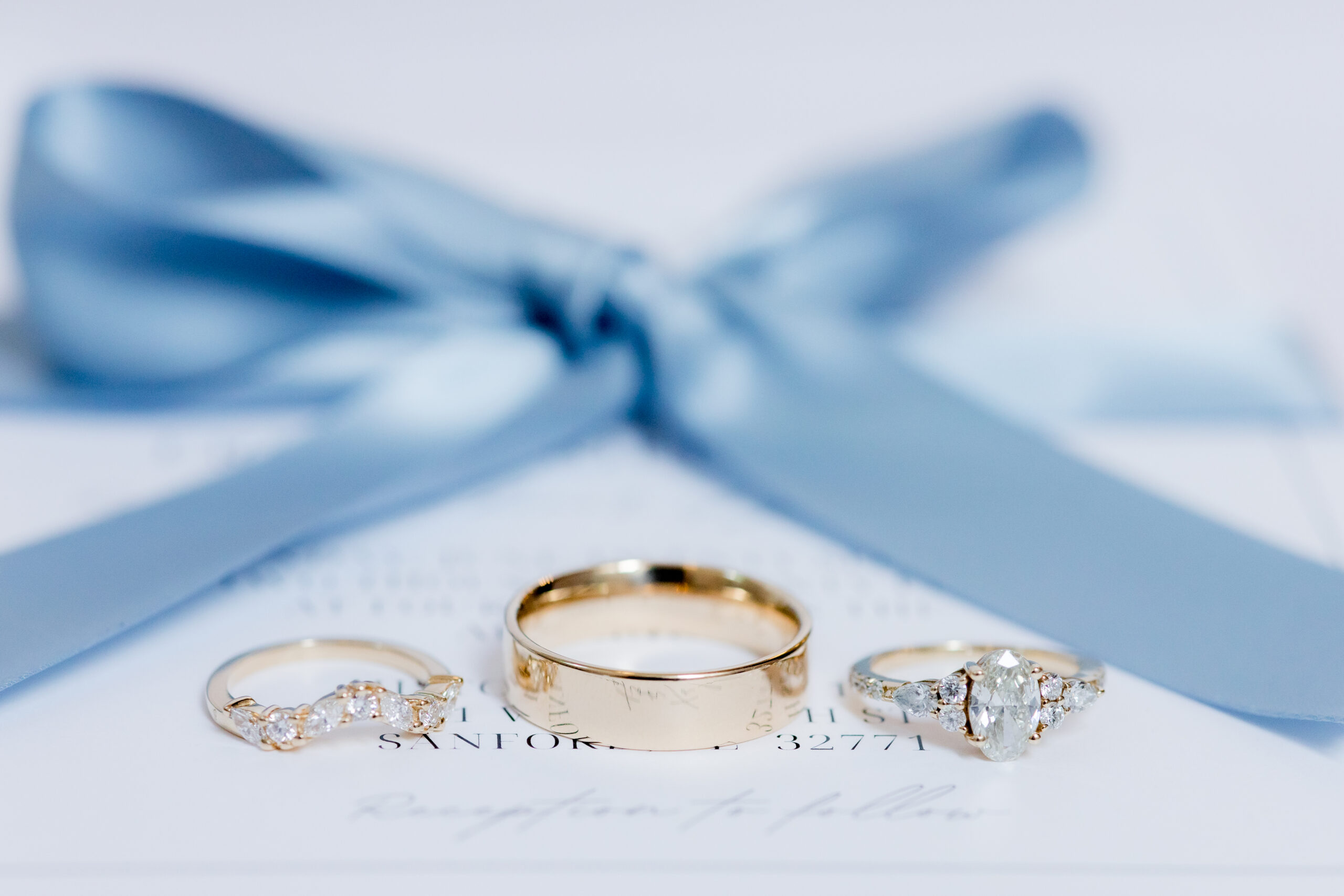 Three wedding rings with a blue bow showing the beauty of the rings.